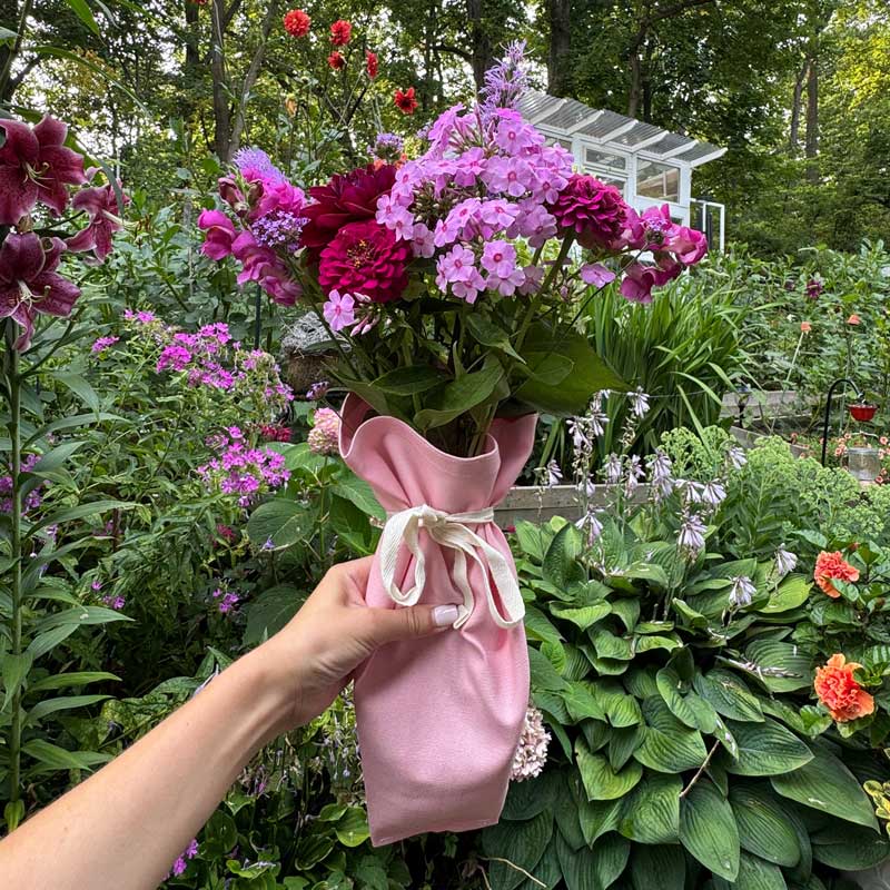 Pink Bouqbags natural canvas bouquet sleeves shown holding a bouquet of pink and red flowers
