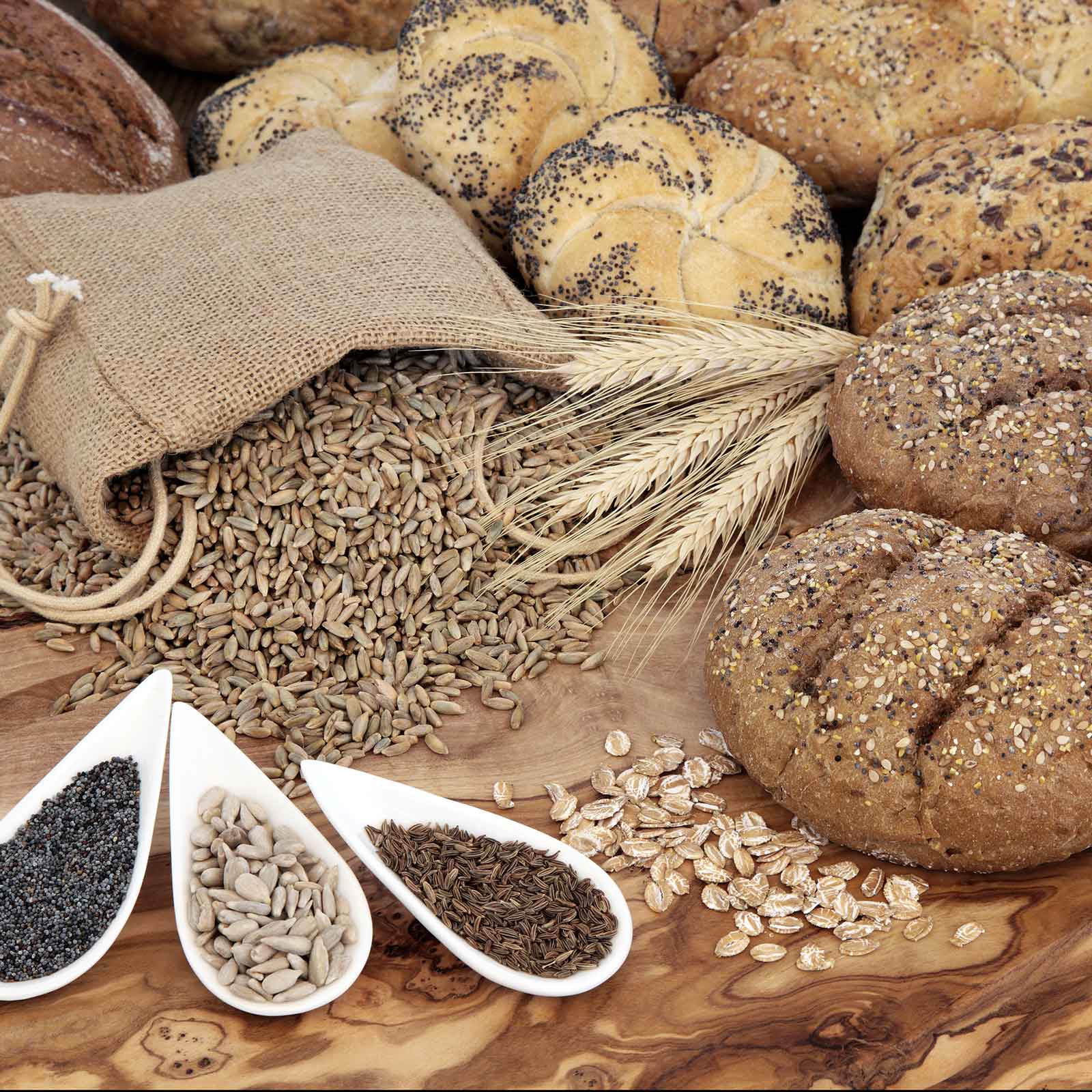 A close-up shot of caraway seeds, on the table, spilling out of a bag, and on bread.
