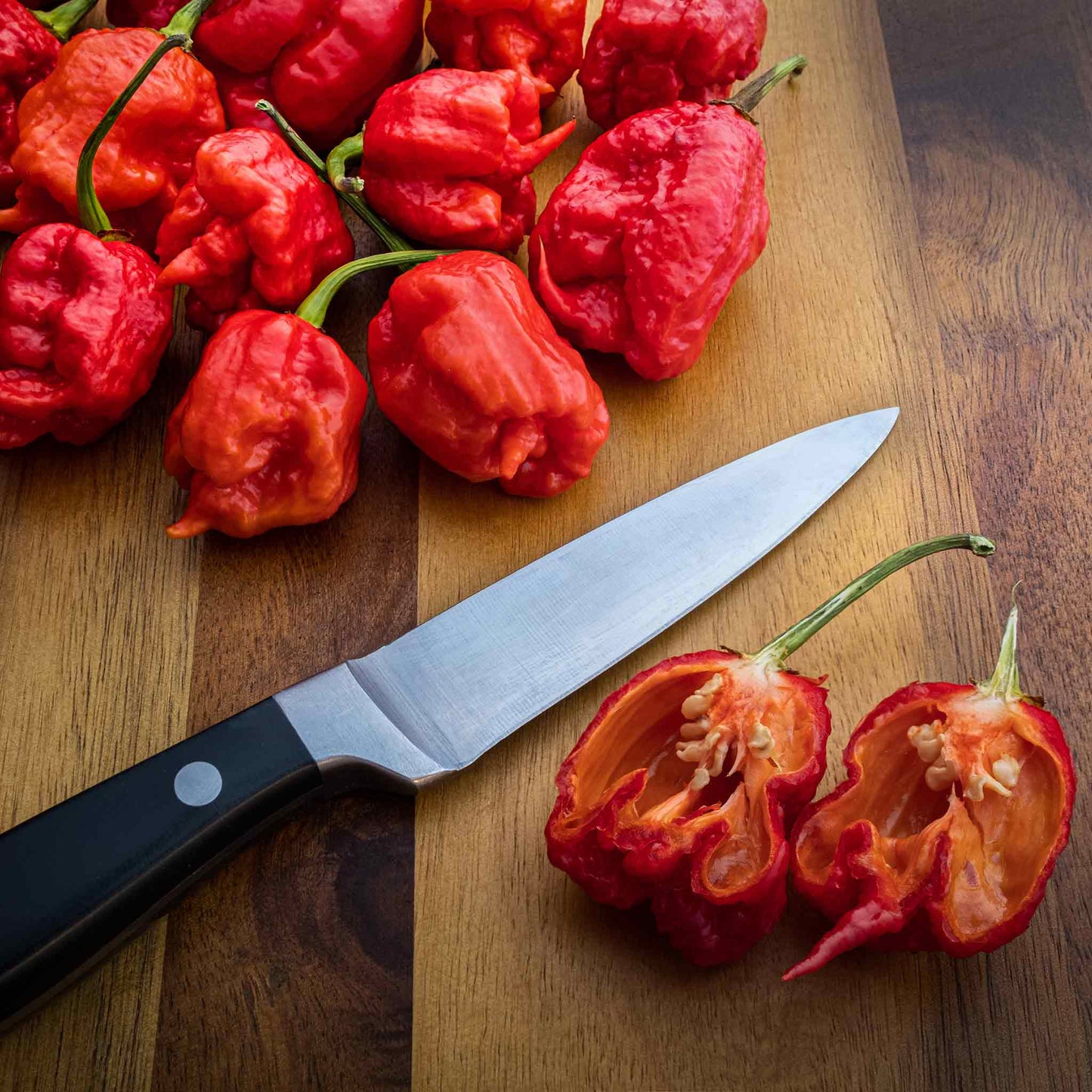 A close-up of a red Carolina Reaper pepper, showing its wrinkled texture and pointed tail.