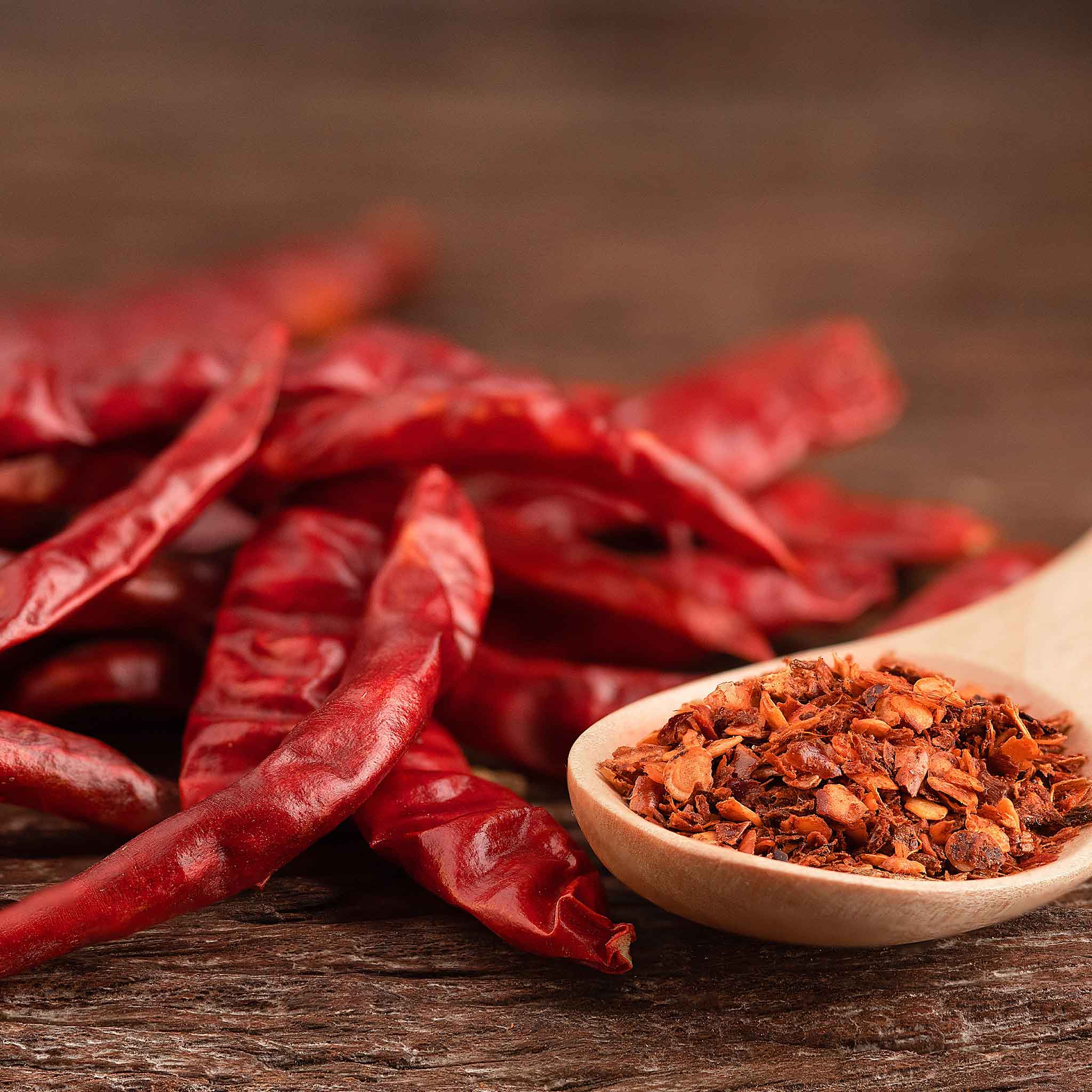 Several slender, Cayenne Long Red Thin peppers are shown with pepper flakes peppers.