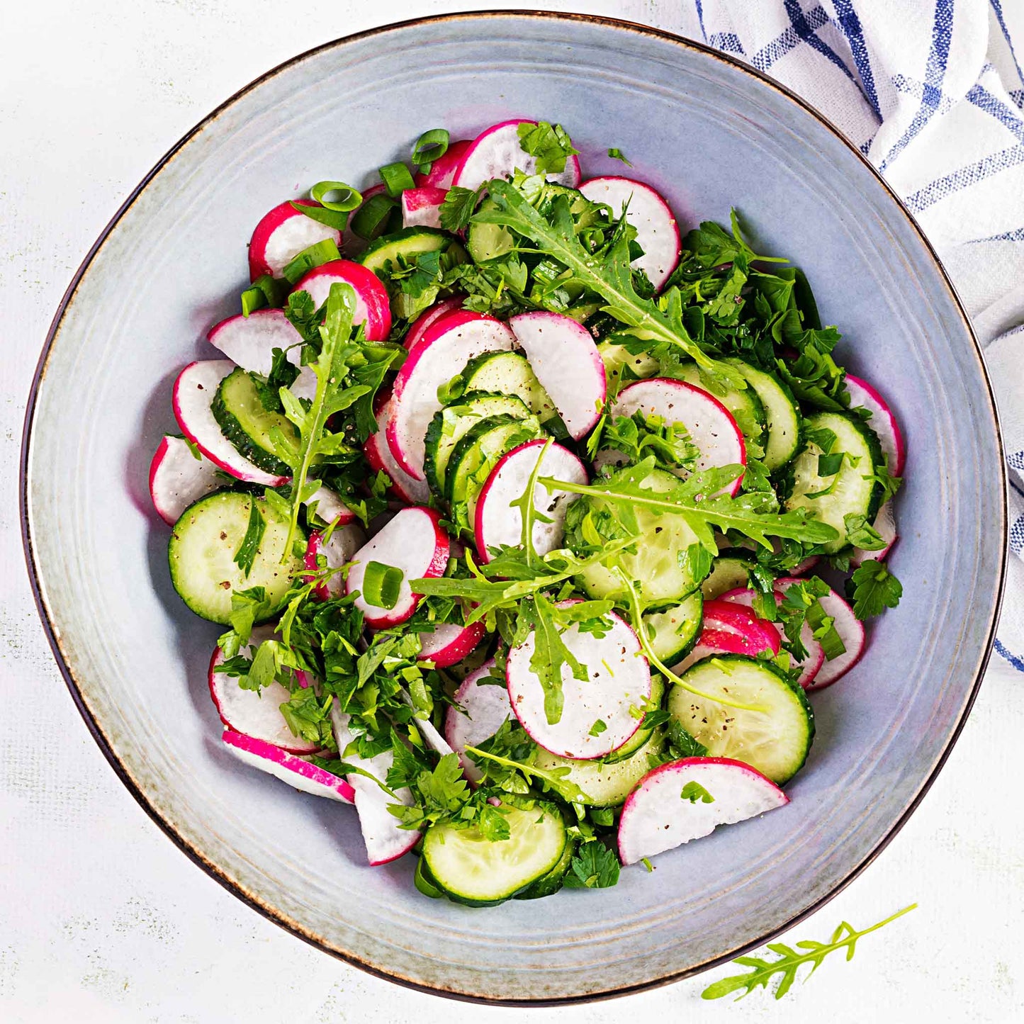A bowl of cut Champion radishes with mixed greens.