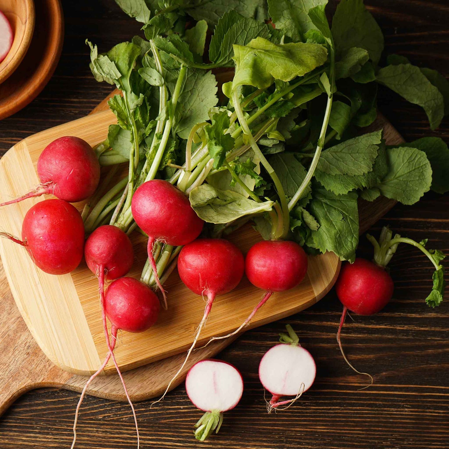 A cluster of vibrant Cherry Belle radishes with green leaves, freshly harvested and ready to eat.