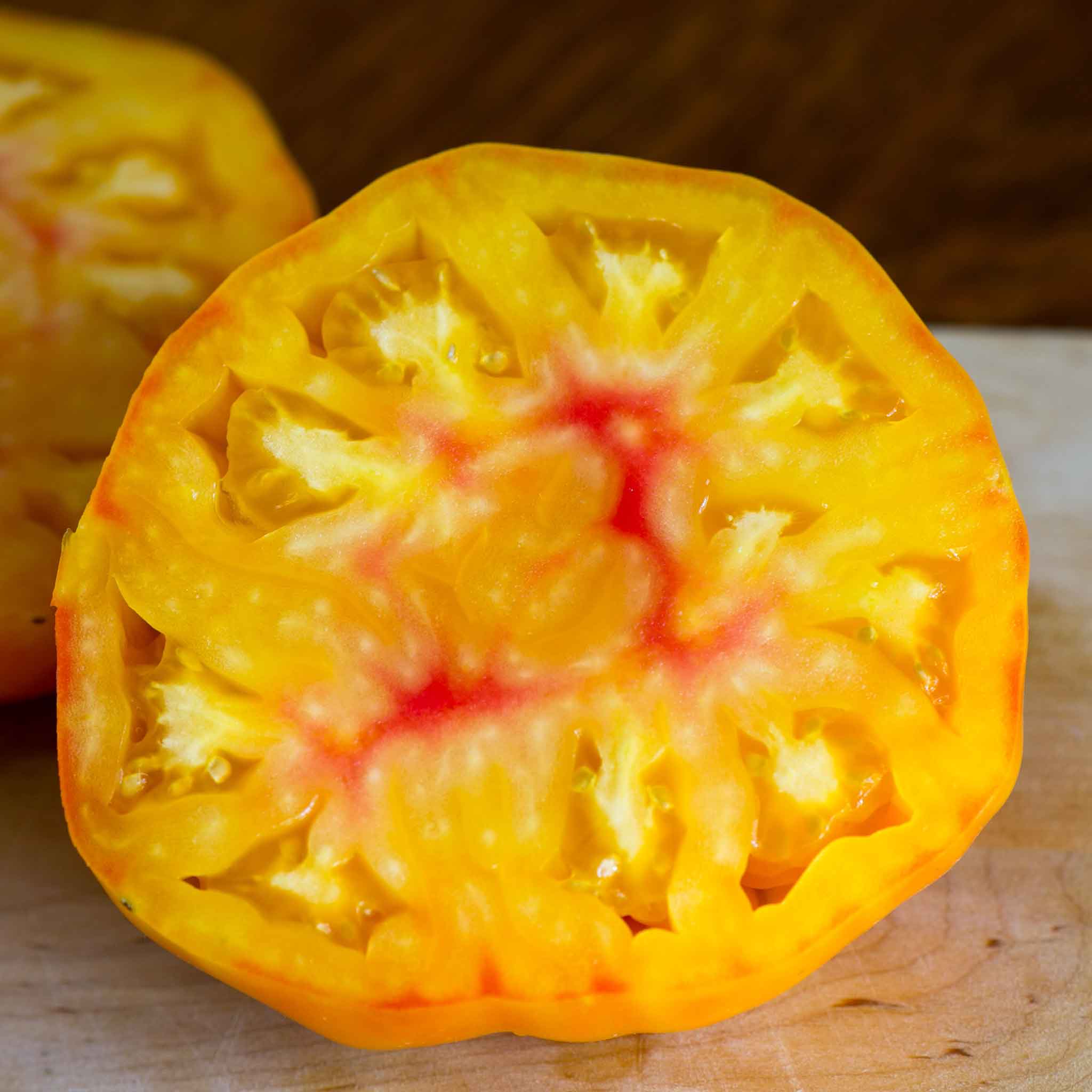 A close-up shot of a striped German tomato, showcasing its unique red and yellow flesh.