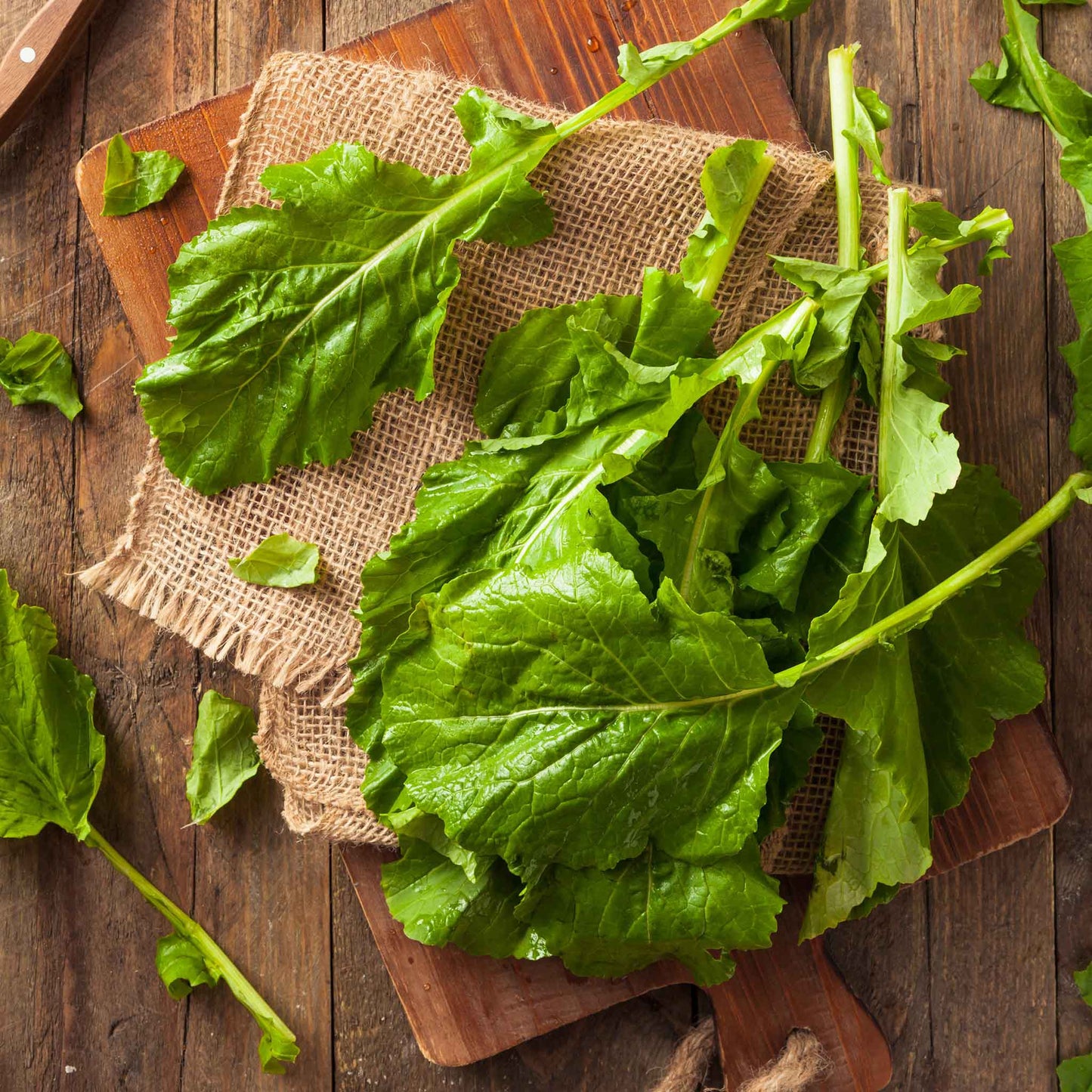 A close-up shot of green Seven Top turnip leaves on a cutting board.