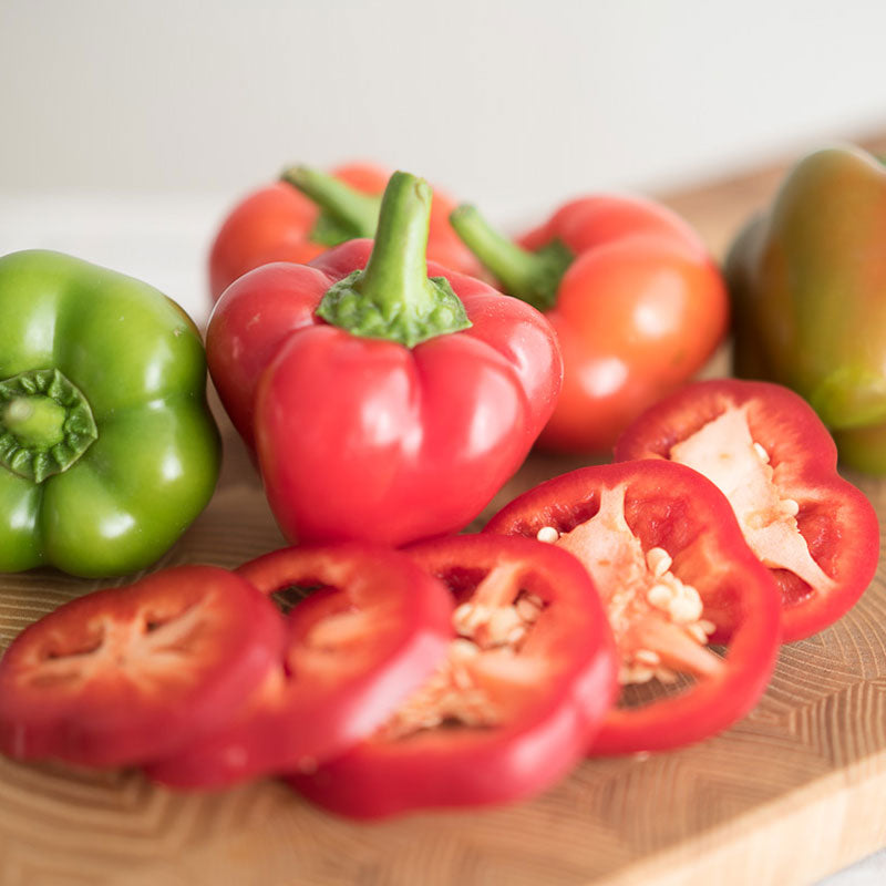 Chili Pie F1 peppers on a cutting board with one pepper sliced in front showing the inside.