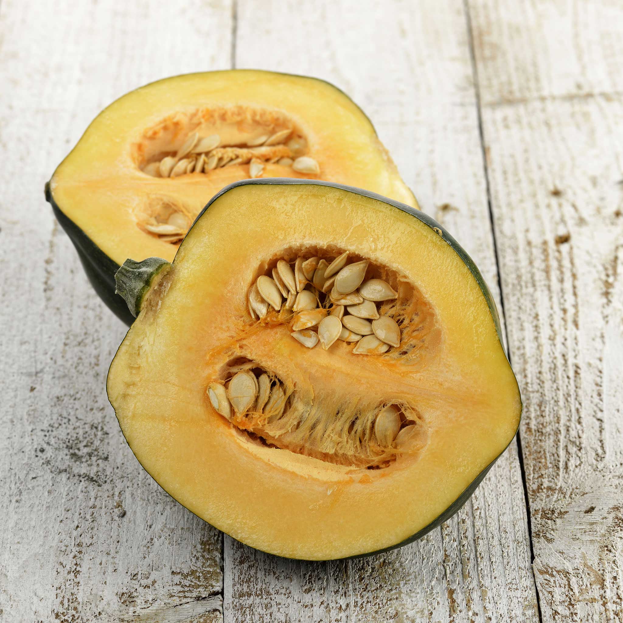 Table King Bush squash sliced in half showing inside flesh and seeds.