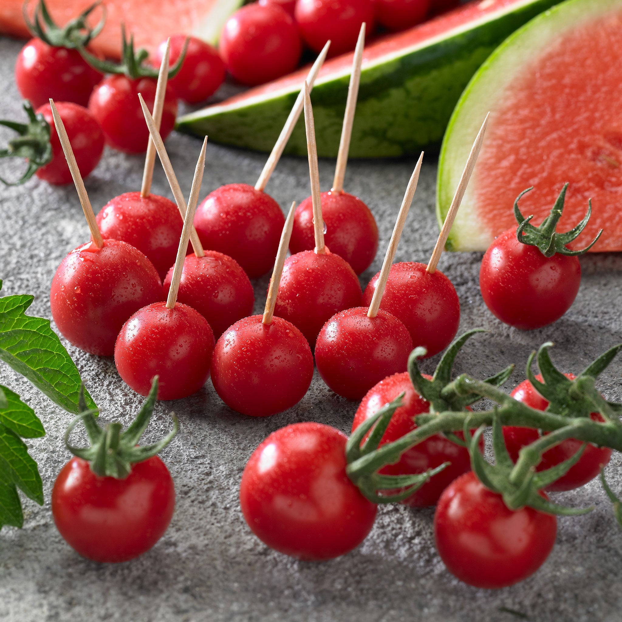 Melon tomatoes with toothpicks in some and green stems on others.