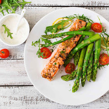 A plate of cooked salmon and mary washington asparagus and tomatoes ready to eat.