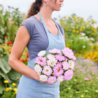 Person holding a bouquet of china aster duchesse rose white flowers in a garden setting