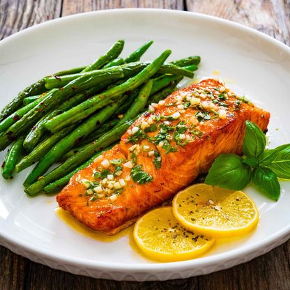 Cooked harvester beans on a plate with cooked salmon and lemon slices.