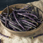 A wooden bowl of purple royal burgundy beans with a neutral background.