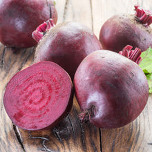 A close-up of several red crosby egyptian beet roots against a light background.