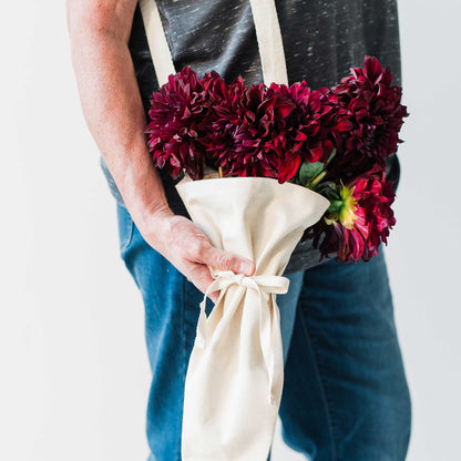 Person holding a bouquet of flowers using the bouqbags gifting tote on a white background