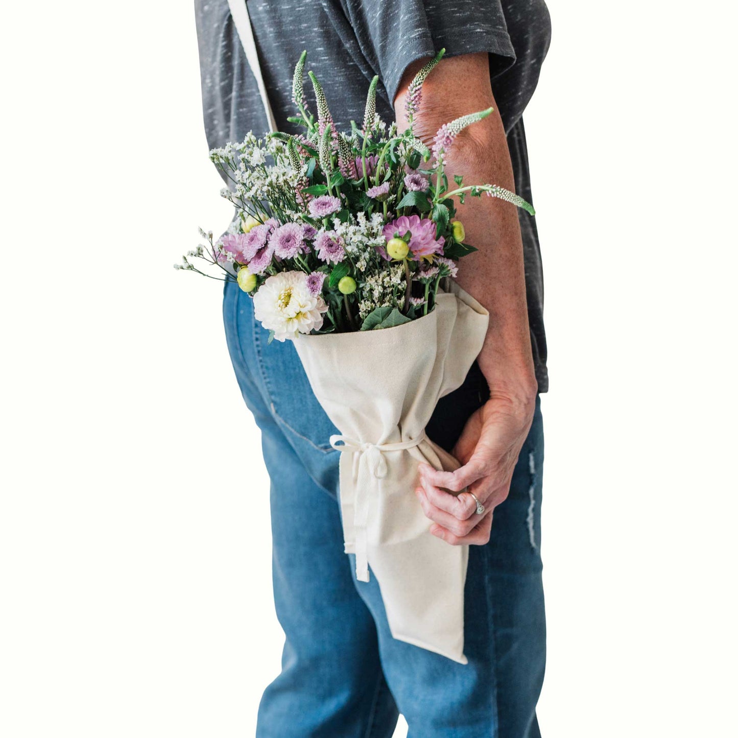 Person holding a bouquet of flowers using the bouqbags gifting tote on a white background