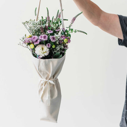 Person holding a bouquet of flowers using the bouqbags gifting tote on a white background