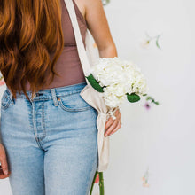 Person holding a bouquet of flowers using the bouqbags gifting tote on a white background
