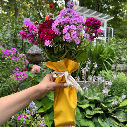 Yellow Bouqbags natural canvas bouquet sleeves shown holding a bouquet of pink and red flowers