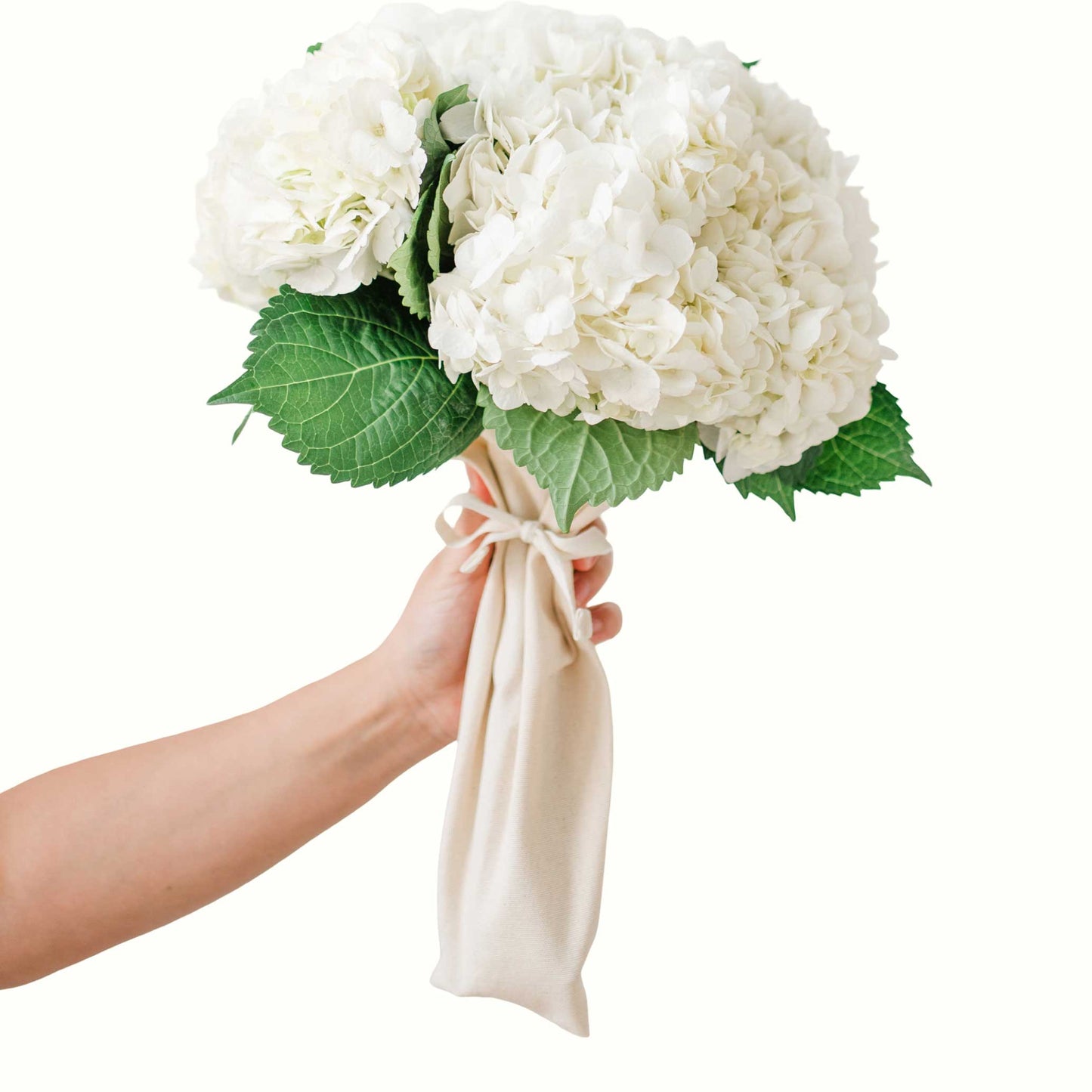 Bouqbags natural canvas bouquet sleeves shown holding a bouquet of white flowers on a white background