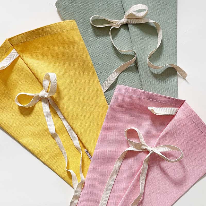 Bouqbags natural canvas bouquet sleeves laying flat with ribbons on a white background