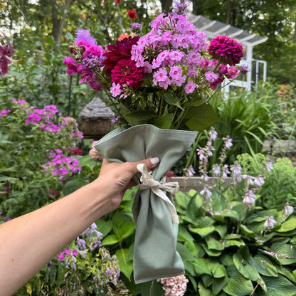 Green Bouqbags natural canvas bouquet sleeves shown holding a bouquet of pink and red flowers