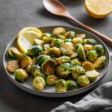 A plate of roasted dagan f1 brussels sprouts with sesame seeds and lemon slices.