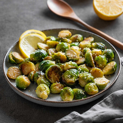 A plate of roasted dagan f1 brussels sprouts with sesame seeds and lemon slices.