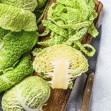 A close-up view of a green savoy cabbage head, showing its crinkled, deeply veined leaves.