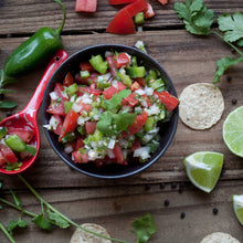 A bowl of salsa with pepper, tomatoes, and onions topped with Eagle Cilantro.