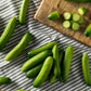 Mini me cucumbers on a striped cloth showing smooth skin, small size, and some slices showing the inside.