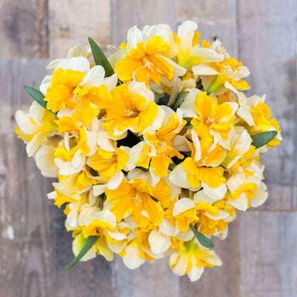 An overhead view of a bouquet of Orangery daffodil flowers in a rustic setting.
