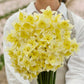 Bouquet of yellow prom dance daffodil flowers held by a person wearing a light gray coat.