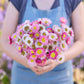 Person holding a bouquet of pink and white paper daisy giant mix flowers with a blurred background