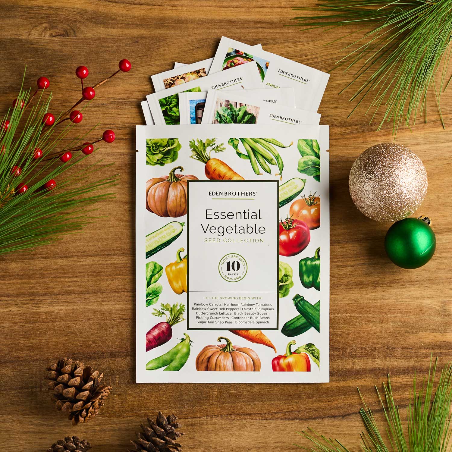 Eden Brothers Essential Vegetable Seed Collection packaging on a wooden surface with holiday decorations.