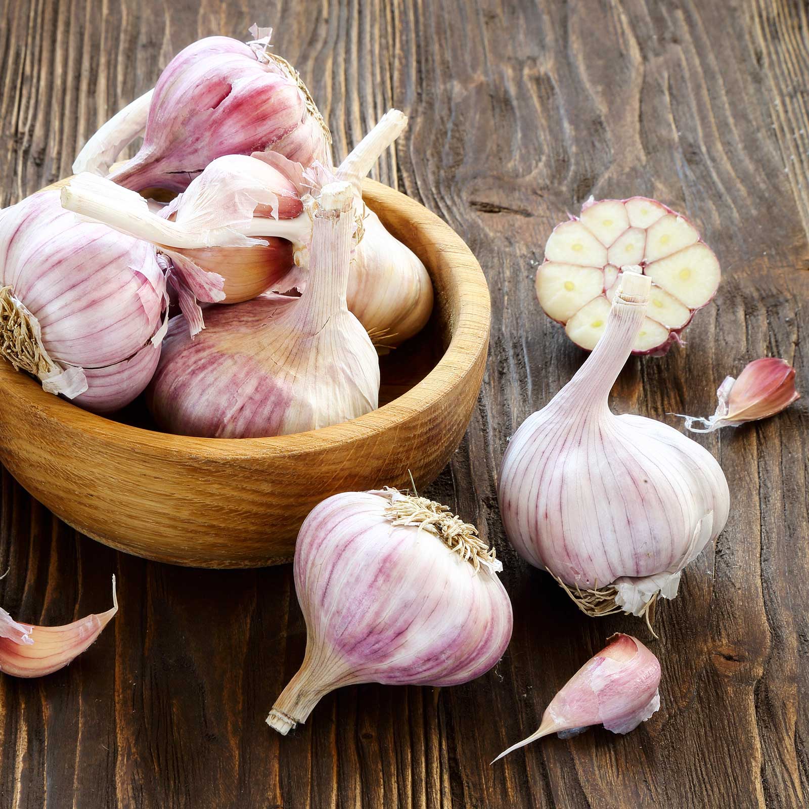 Garlic duganski bulbs in a wooden bowl and table with long stems