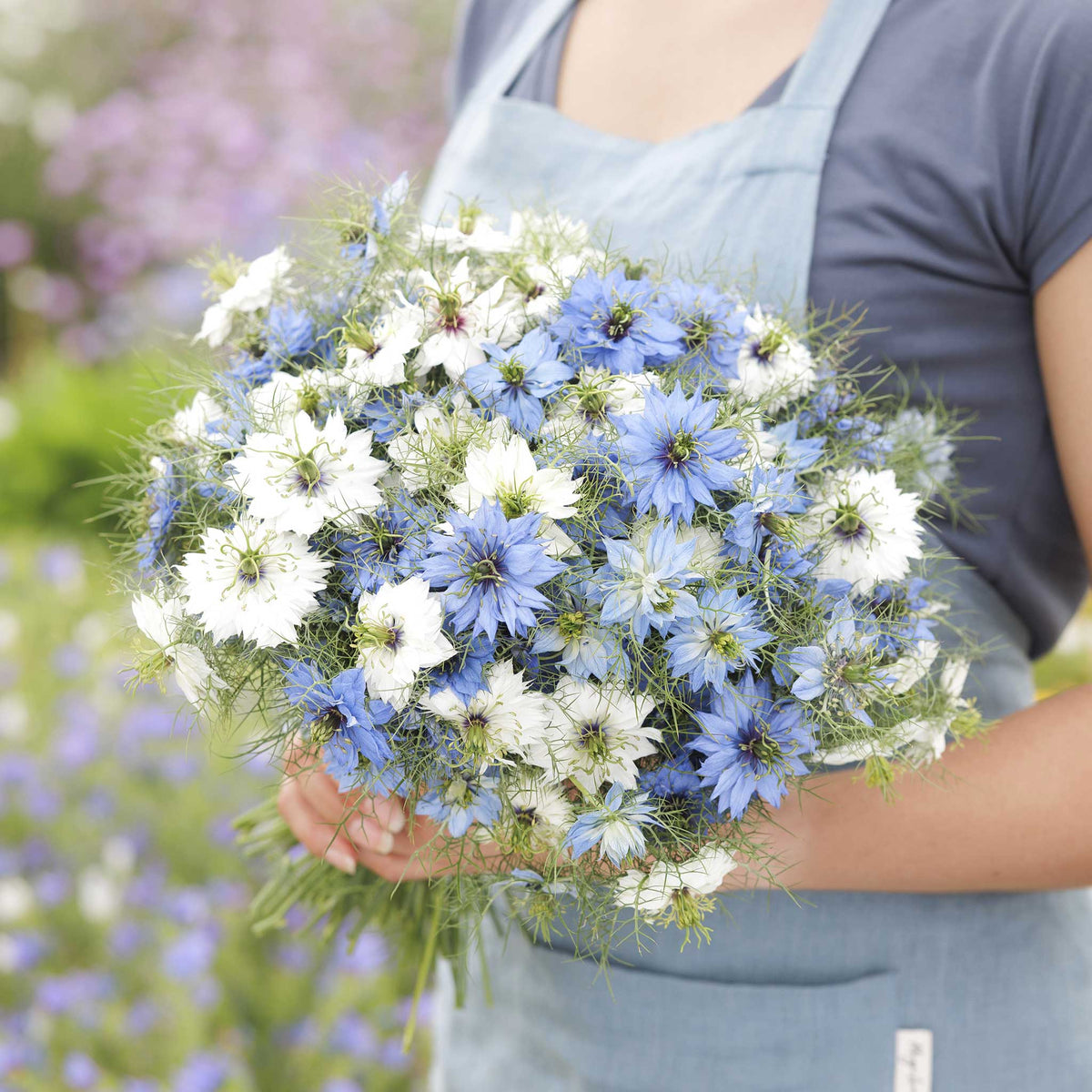 A person holding a bouquet of love in the mist mixed flowers in a natural setting