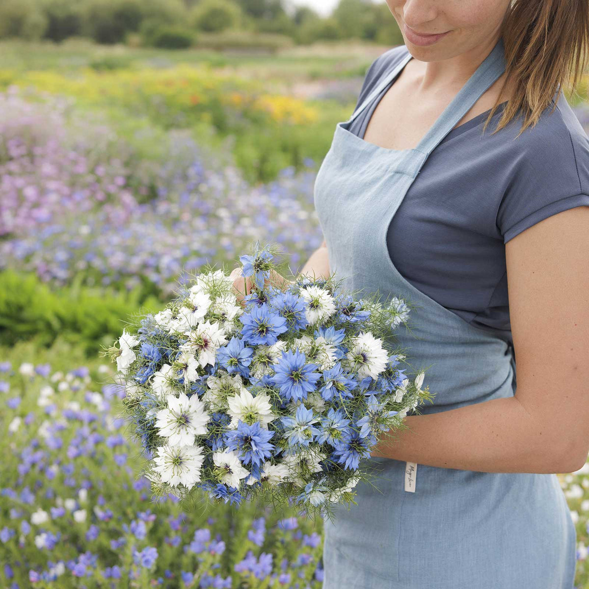 A person holding a bouquet of love in the mist mixed flowers in a natural setting