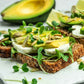 Avocado toast with microgreen sprouts and seeds on a white plate