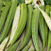 A close-up shot of several Cow Horn okra pods in a pile with some sliced open showing the white interior.
