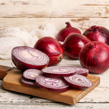 Vibrant Red Creole onions on a wooden background with several sliced onions in the foreground.