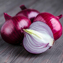 Several vibrant ruby red onions with a papery skin and vibrant interior, resting on a white background.