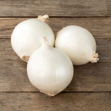 Three white ebinezer onions on a wooden surface