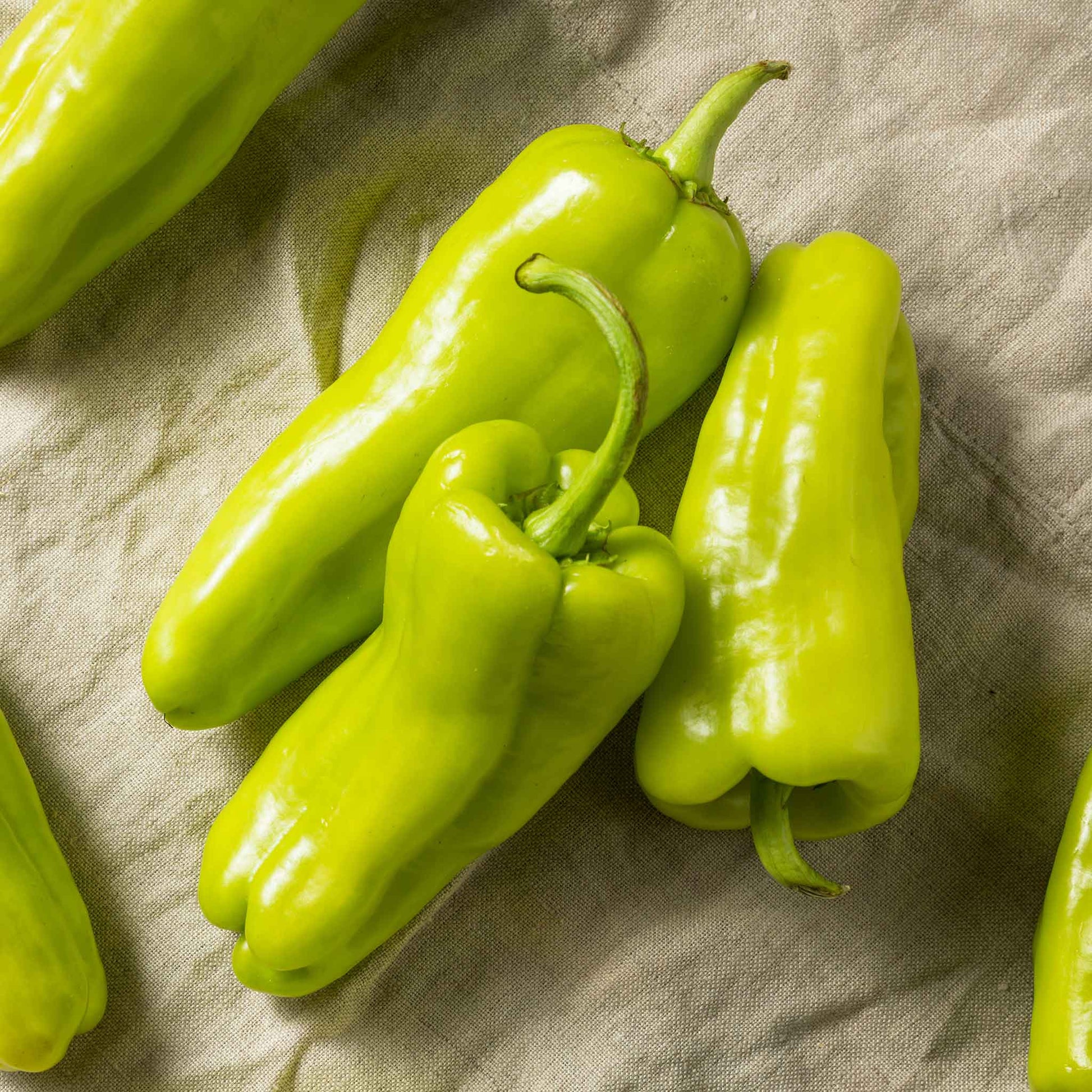 Green Cubanelle peppers with a slightly wrinkled skin and a long, tapering shape.