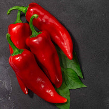 Vibrant red Marconi peppers, elongated and glossy, sits on a dark background.