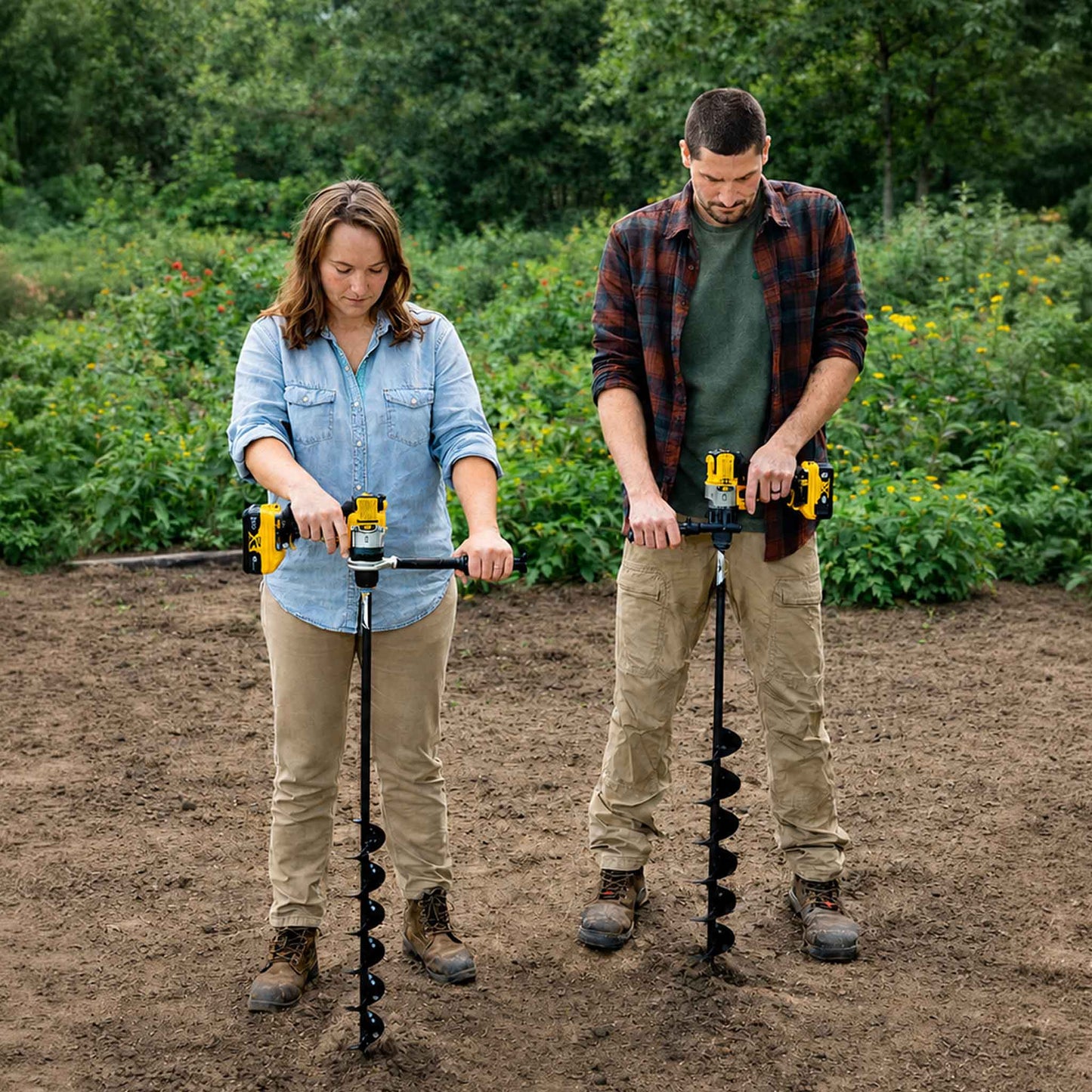 Two people using the power planter bulb planting auger extended length in a garden patch
