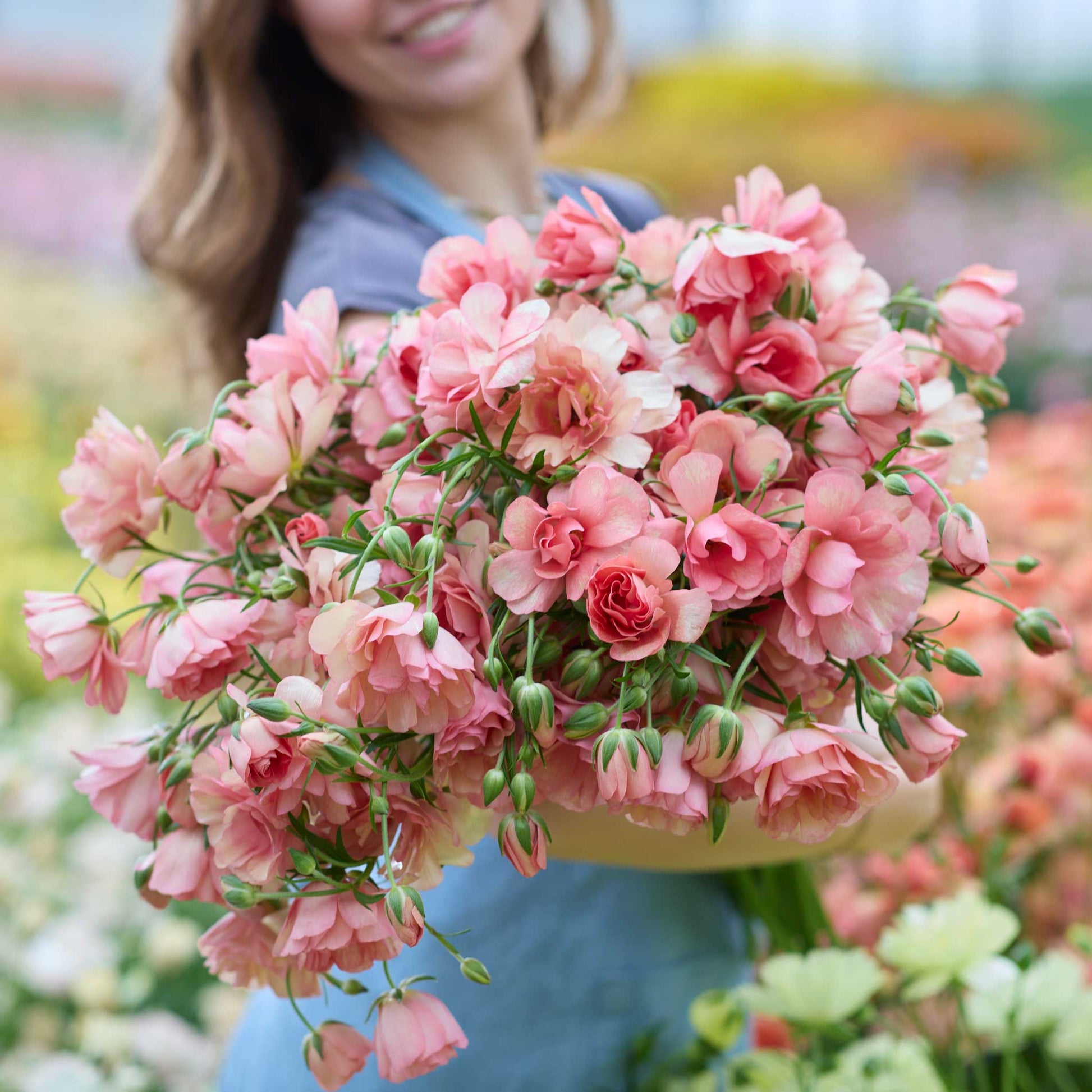Bouquet of pink butterfly eris ranunculus flowers held by a person in a garden setting