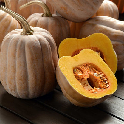 Autumn Frost Squash on a wooden table showing orangish skin and one cut open revealing the orange flesh.