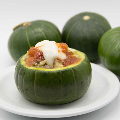 Cupcake squash hallowed out and filled with a soup with other green squash in the background