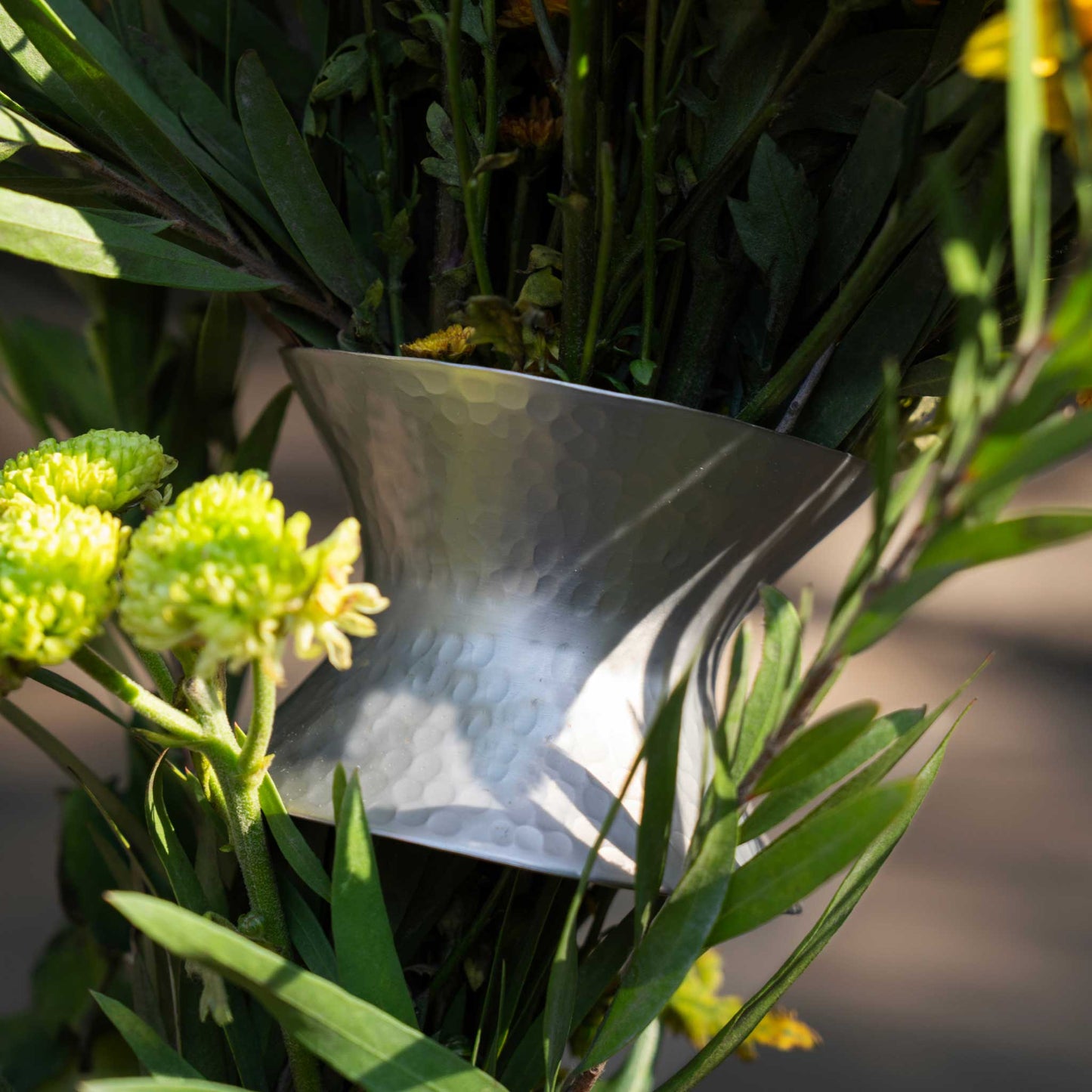 A close up of The collective floral bouquet ring showing its use and hammered metal finish