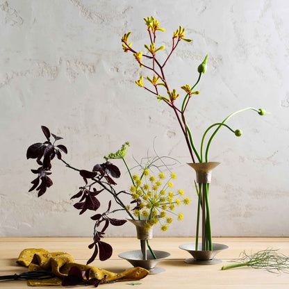 Two arrangements using the collective hammered metal stem vase and bouquet rings on a wooden table and white background