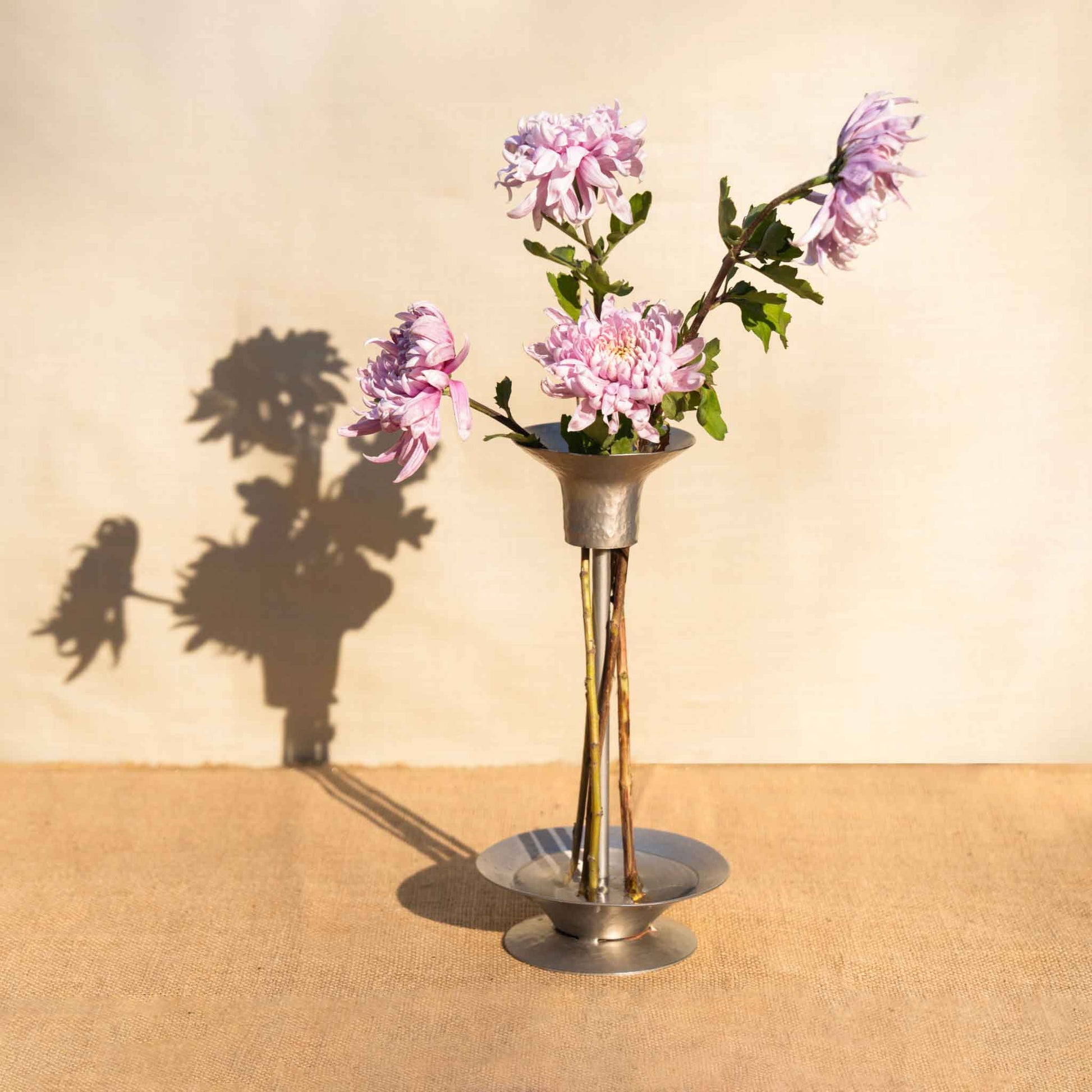 An arrangement using the collective hammered metal stem vase and bouquet ringson a wooden table and neutral background